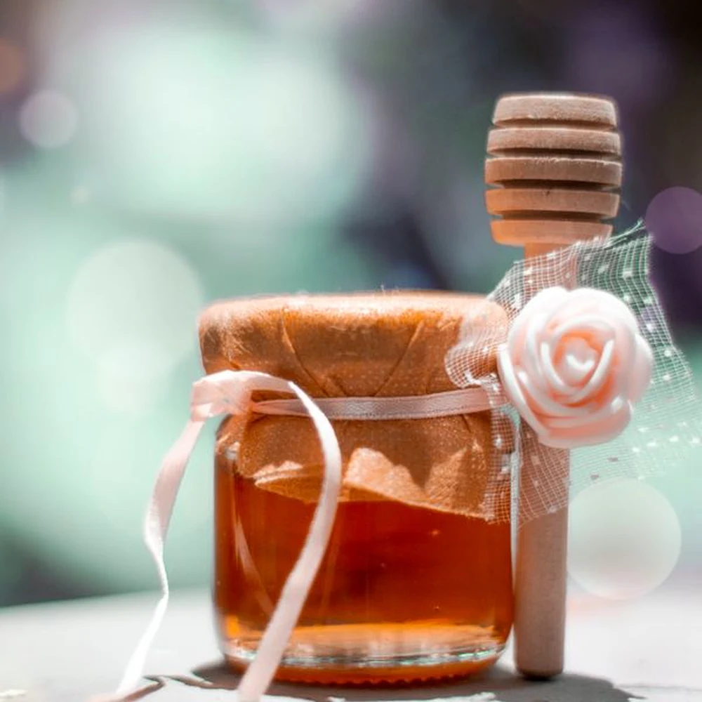 Honey jar with a wooden dipper and decorative ribbon